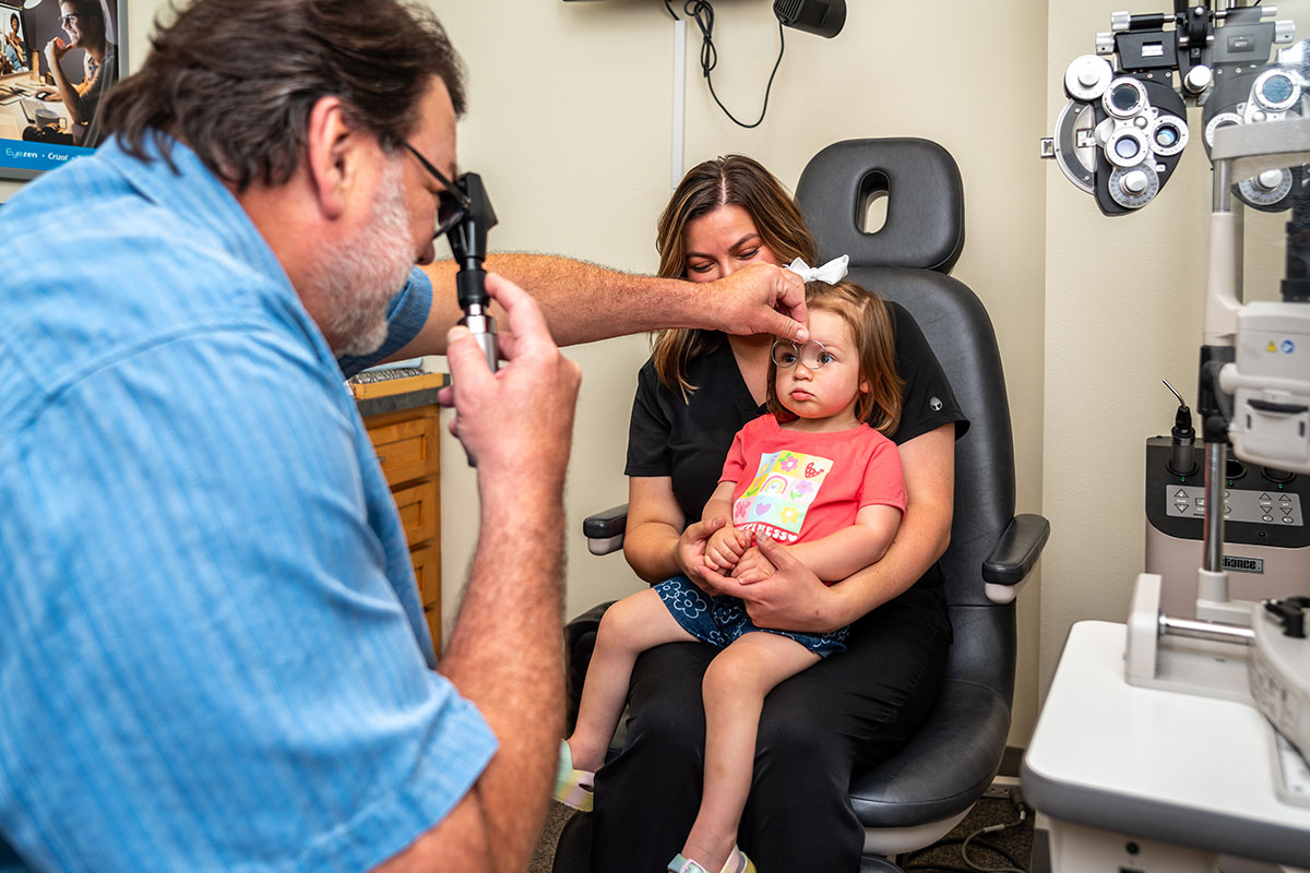 Dr. Kraig Stasney conducting a pediatric eye exam on a young patient